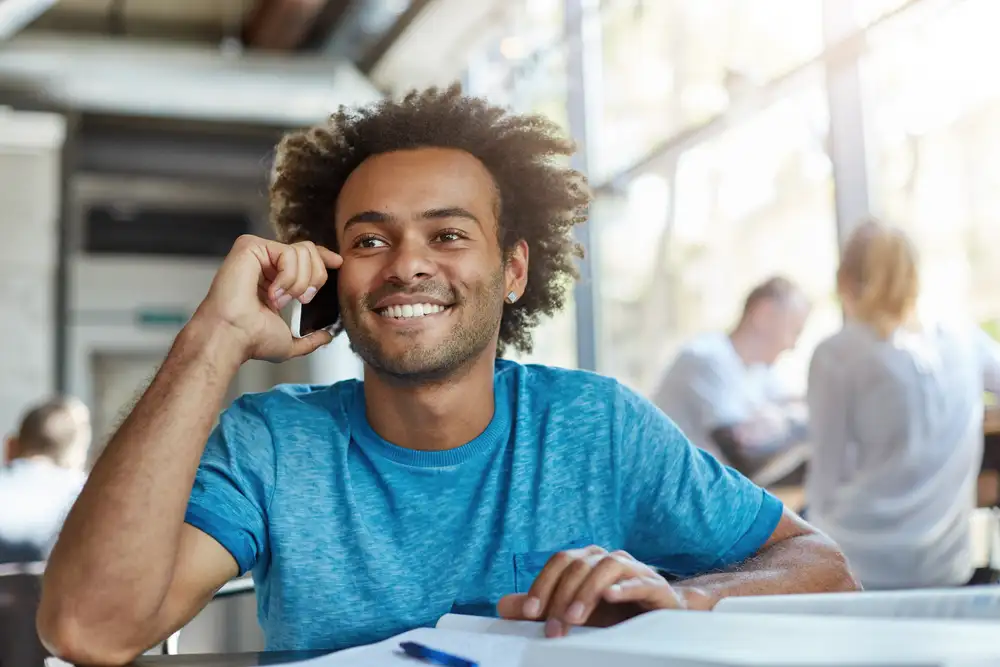 Man smiling during a phone conversation at his desk
